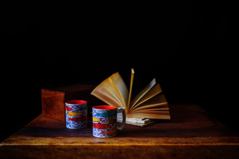 Brightly coloured Spanish coffee cups and an open book photographed as a table top still life scene