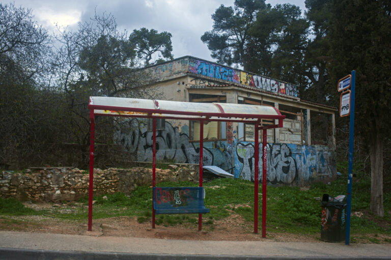Painted old bus stop in front of graffiti beside an urban park