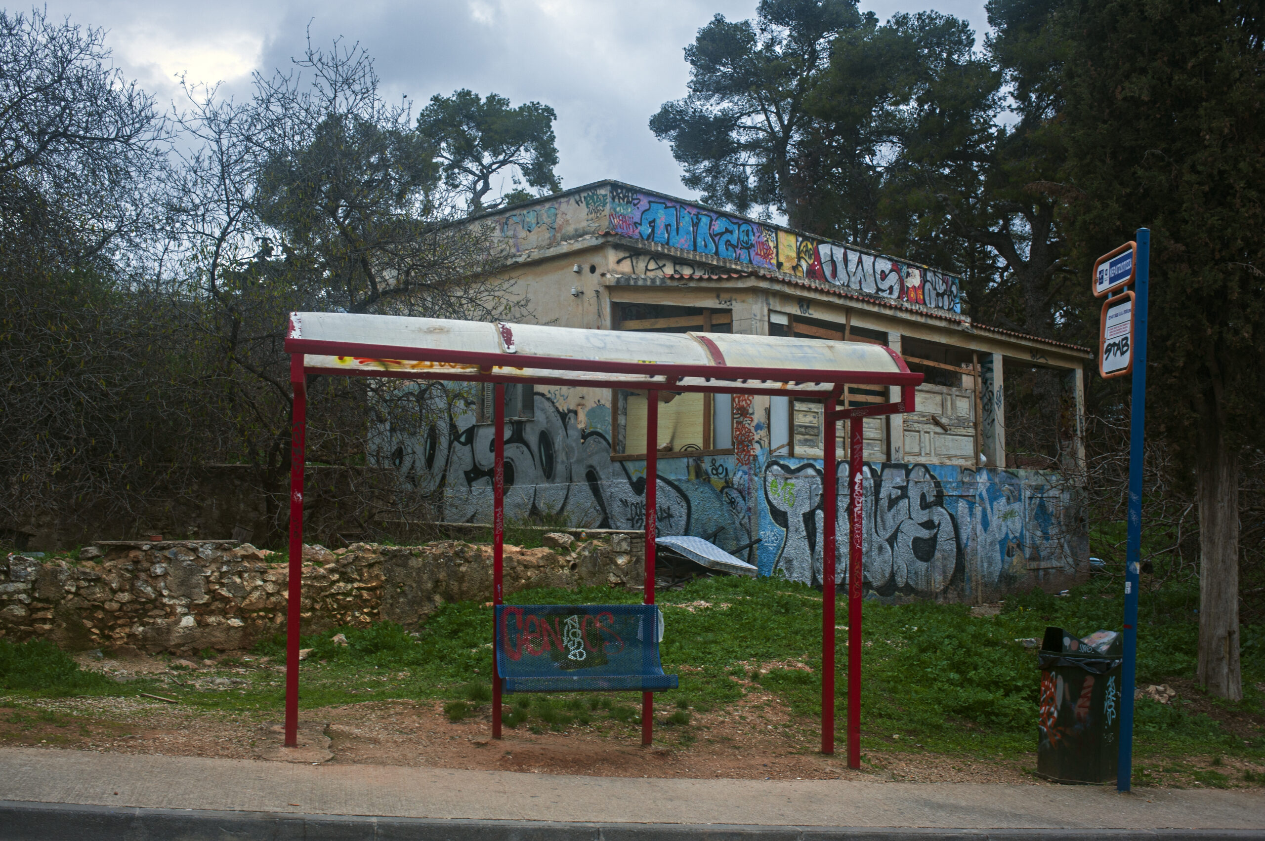 Painted old bus stop in front of graffiti beside an urban park