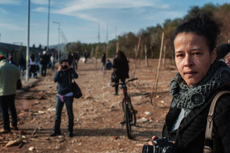 A photo of me with my camera in the foreground and people moving around in the background