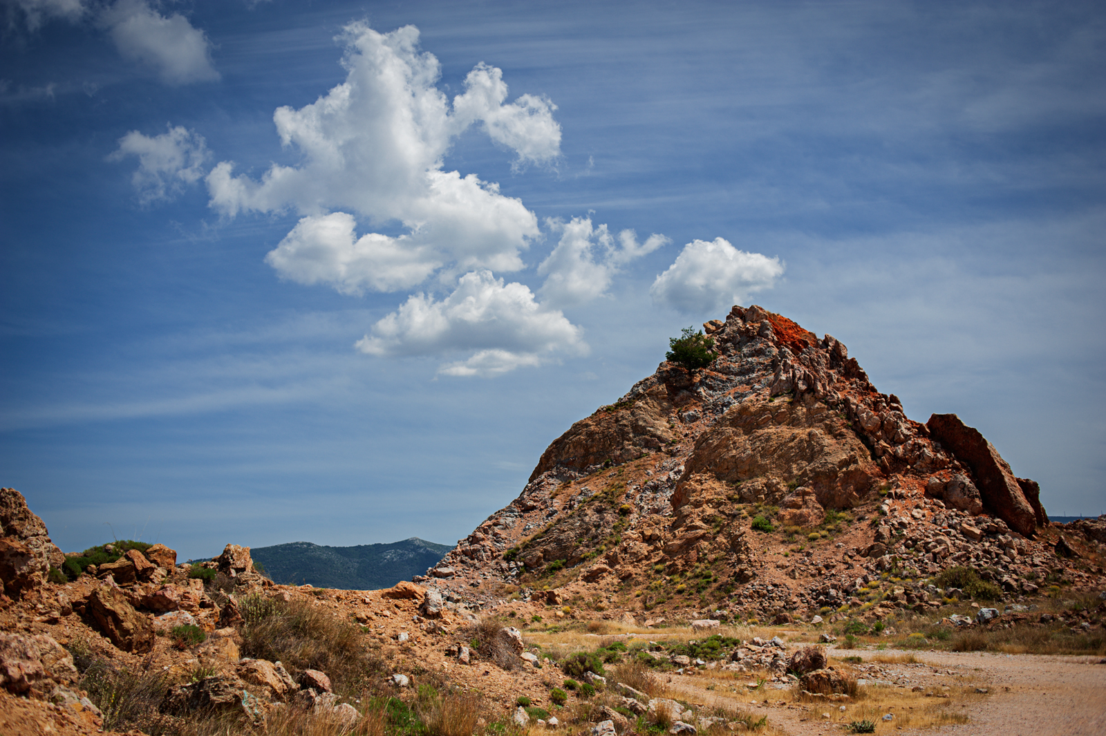 The top of Turkish Mountains in Athens with white fluffy clouds in a perfect formation in the sky.