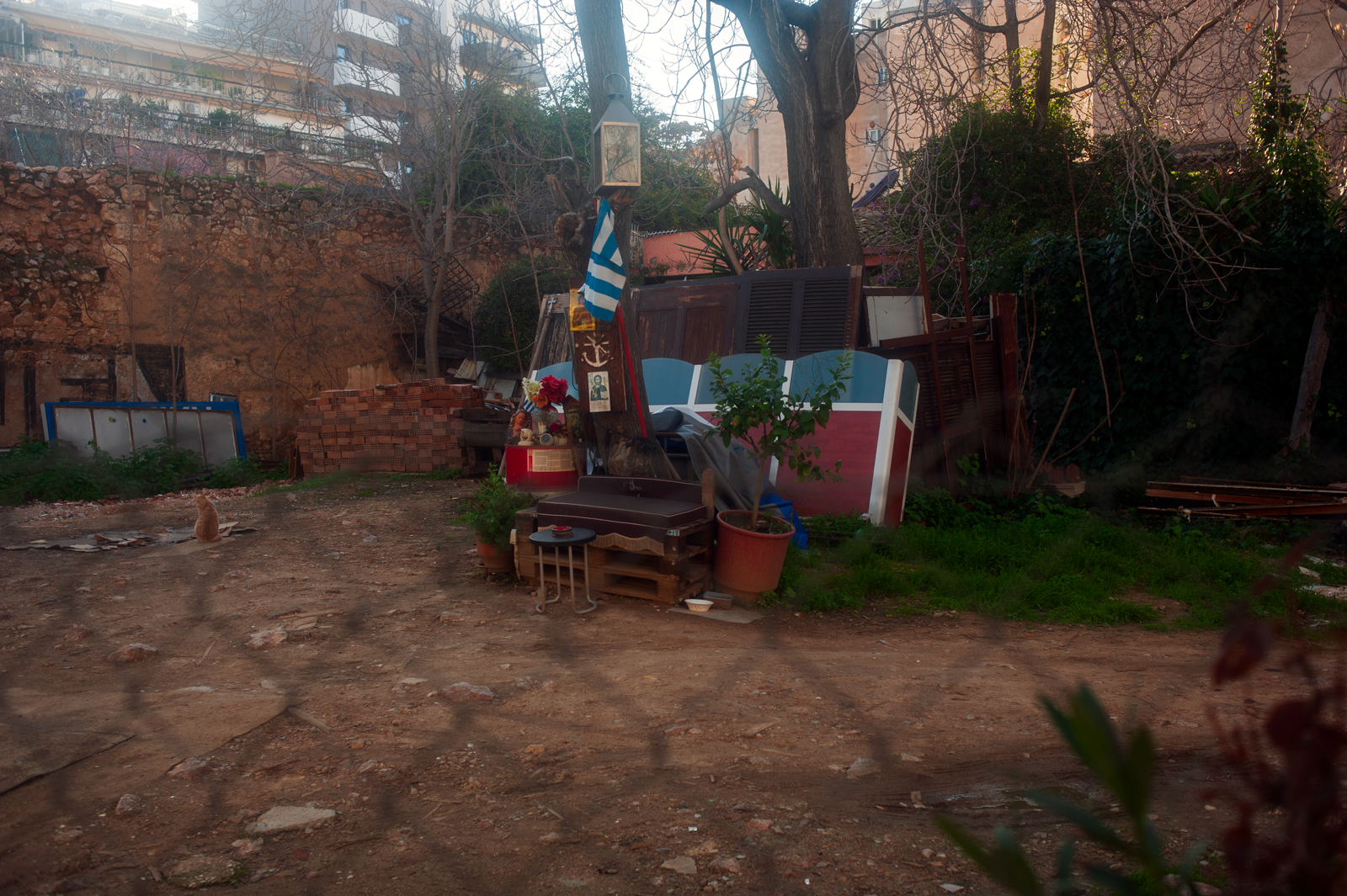 A deserted yard with junk around where someone has made a little refuge.