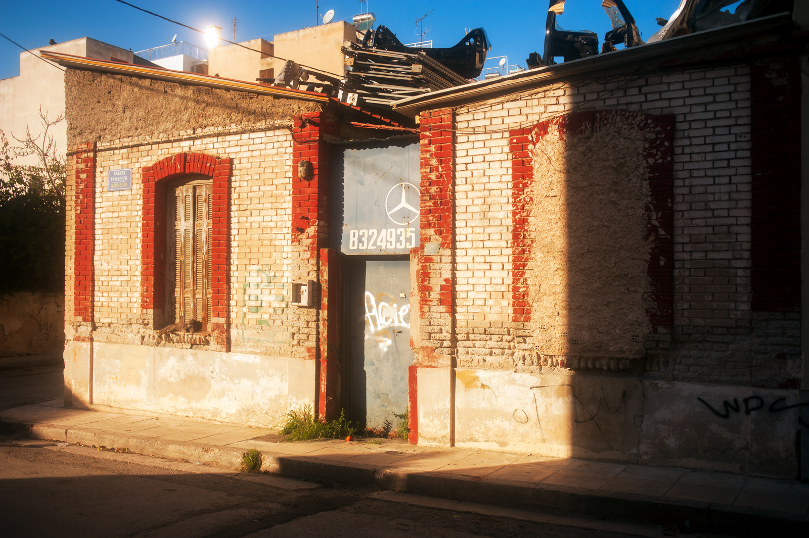 An old Mercedes repair shop with a pile of broken cars on the roof.