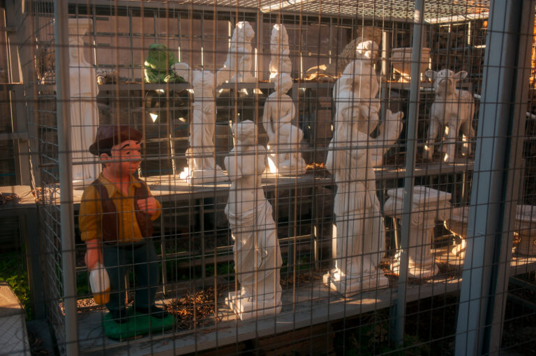 Marble memorial statues in the yard of a marble workshop with an odd comic character made of stone beside them.