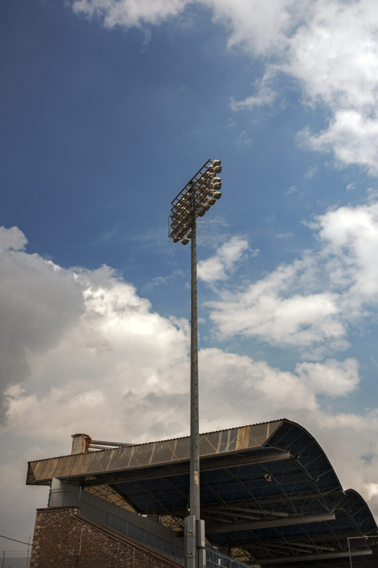 A colour photograph of an old football stadium in the early evening. Strong clouds in the background.