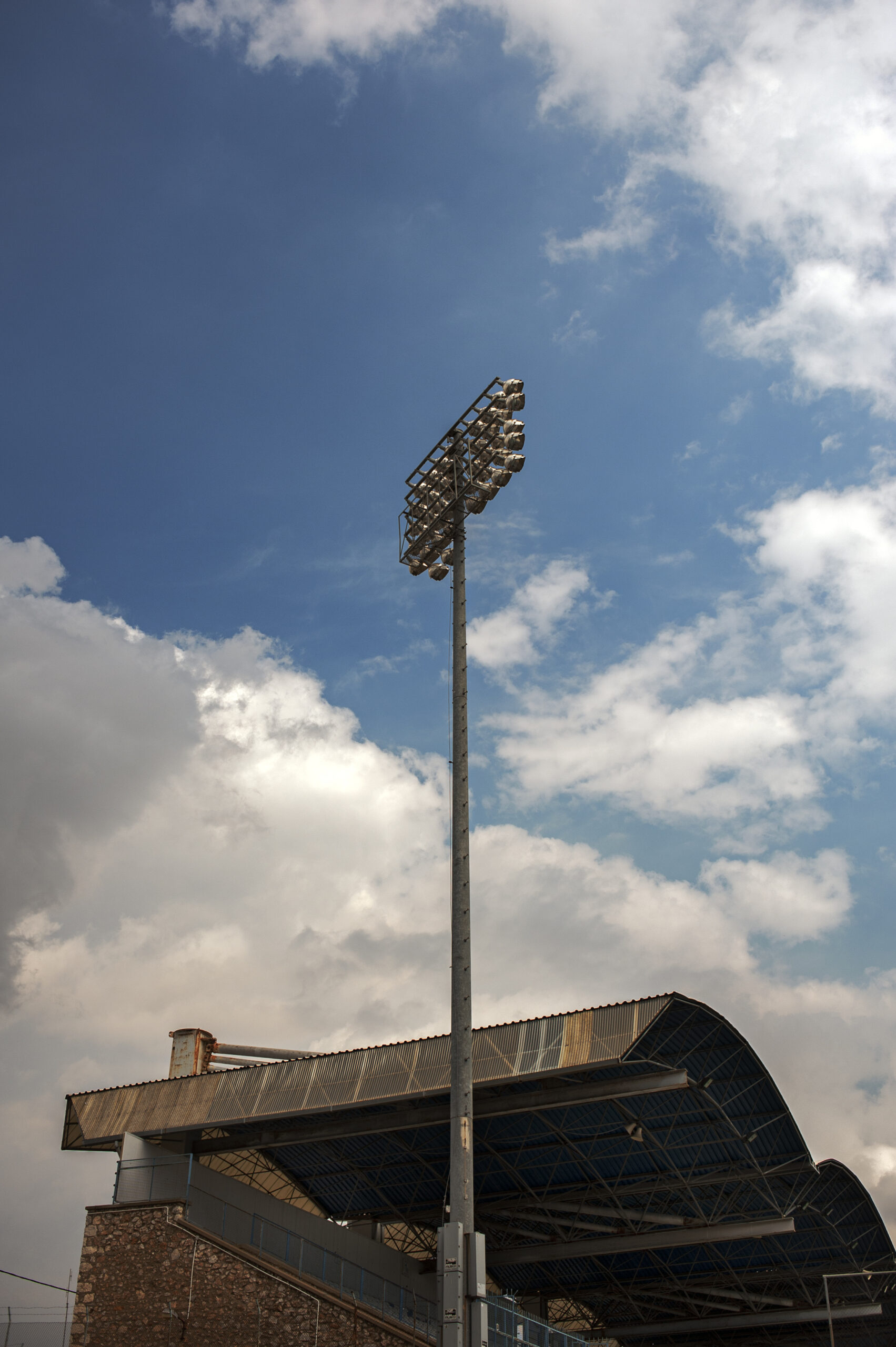 A colour photograph of an old football stadium in the early evening. Strong clouds in the background.