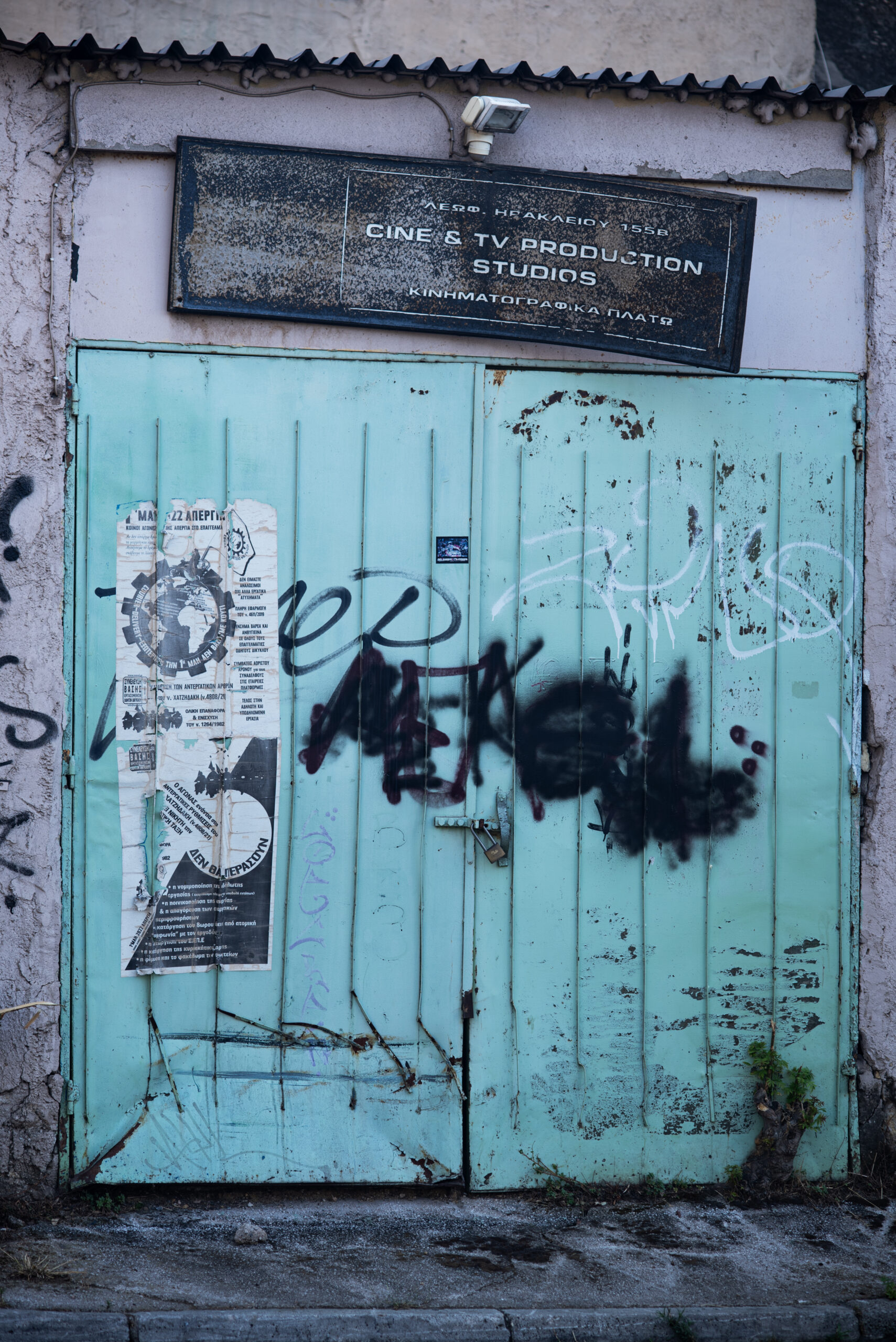 A colour photograph of a vintage door that used to lead to a film production company building. It is worn and decayed but the beautiful original blue colour still shows.
